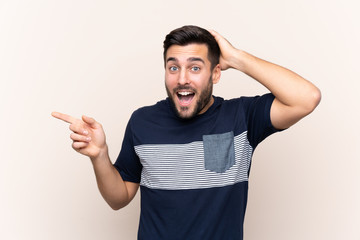 Young handsome man with beard over isolated background surprised and pointing finger to the side