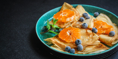 crepes with citrus, jam and berries (thin pancakes, mandarin, blueberry) menu concept. background. top view. copy space