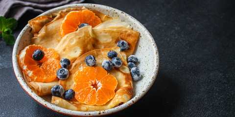 crepes with citrus, jam and berries (thin pancakes, mandarin, blueberry) menu concept. background. top view. copy space