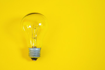 Incandescent light bulb on a yellow background.