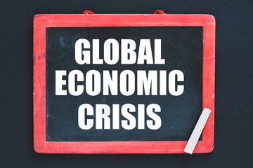 The global economic crisis written on a chalk board and a black background. Business concept.