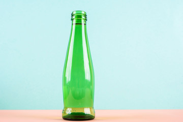 A glass water bottle is bright green on a light background.