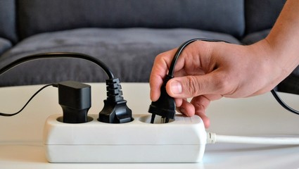 Three different electrical plugs connected to a power strip or extension block. Electric plugs with...