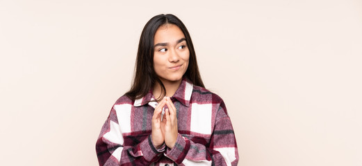 Young Indian woman isolated on beige background scheming something
