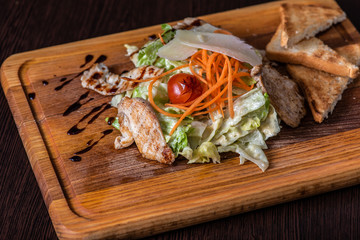Greek salad with chicken salad, tomatoes on a wooden tray