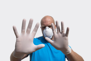 Soft focus man wearing surgical mask with gloves on white background shows stop.