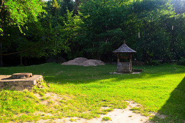 A green garden in the backyard with a wooden hut and lawn. Beautiful forest with a glade and a country house. Countryside lente housing, holiday home. Wooden Old Russian Architecture.