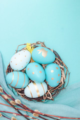 Easter background with Easter eggs in bird nest on blue backgrou