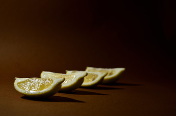 four slices of yellow lemon on a brown background horizontal orientation
