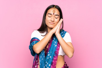 Young Indian woman with sari over isolated background making sleep gesture in dorable expression