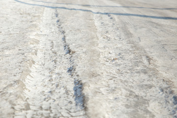 Dangerous driving conditions. Icy road with tracks from the wheels of cars . The concept of safe driving on a winter slippery track. The texture of the ice road.