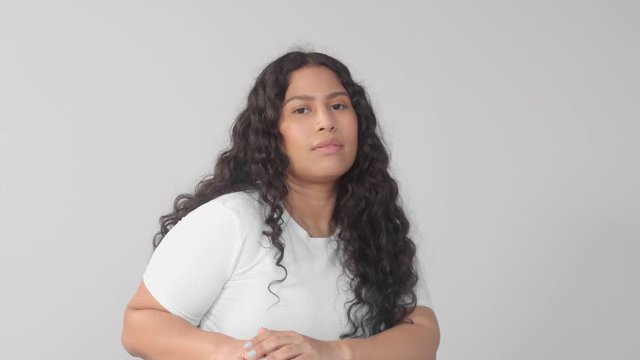 Mixedr ace young plus size woman without makeup in studio on grey background poses to the camera and laughing at the end. New beauty, new identity without gender 