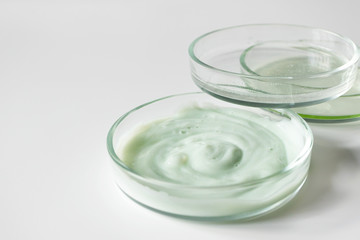 Variety cosmetic products in petri glass dishes on white background with selective focus. Body care and hygiene