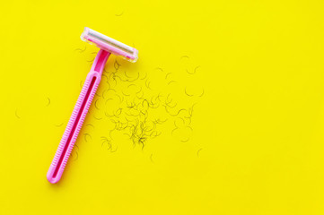 women's shaving machine pink and hair on a yellow background. The concept of women's shaving.