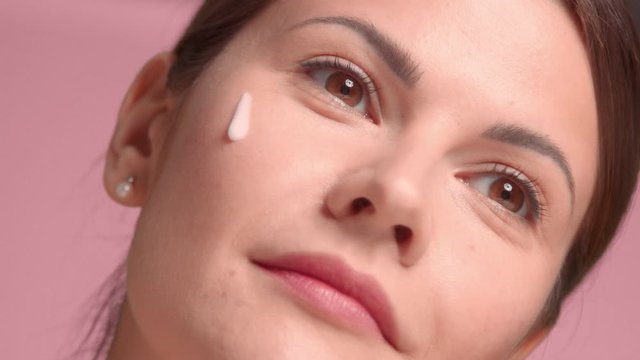 Closeup how 30s woman put some facial treatment on dropper on cheek and massage it to skin