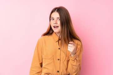 Ukrainian teenager girl over isolated pink background surprised and pointing front