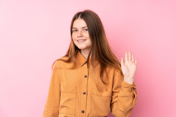 Ukrainian teenager girl over isolated pink background saluting with hand with happy expression