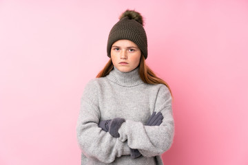 Ukrainian teenager girl with winter hat over isolated pink background keeping arms crossed