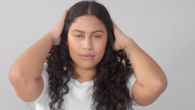 panned dolly portrait of young plus size mixed race woman without makeup watching to the camera and touche her curly long hair