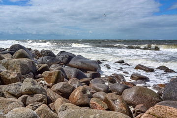 Large stones at the beach by the Jons Kapel (John's Chapel) - a 22-metre high solitary rock which resembles a church tower, Bornholm island, Denmark.