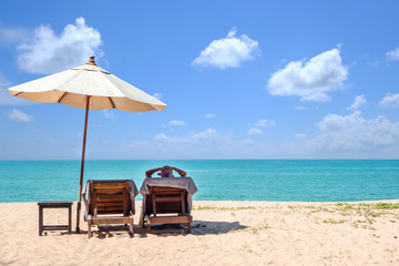 Relaxing bed chairs with parasol on beautiful beach with blue sky background with copy space.