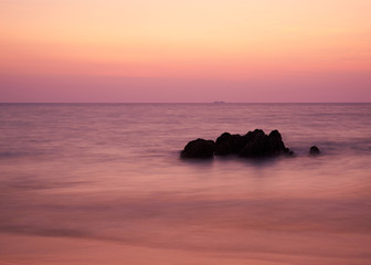 Long exposure scene of beautiful sunset sky and rocks in the sea
