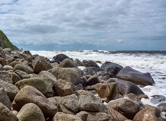 Large stones at the beach by the Jons Kapel (John's Chapel) - a 22-metre high solitary rock which resembles a church tower, Bornholm island, Denmark.