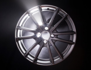 Obraz premium Modern beautiful car alloy wheel in the form of rays that is highlighted by rays of light and sparkle, black background