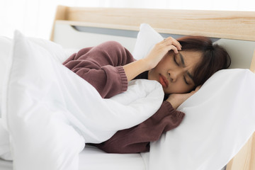 Asian woman sleeps and uses both hands to hold her head because she has stress or headaches from life problems or illness.