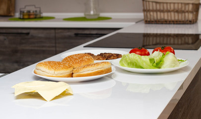 The ingredients are in the kitchen in the form of cheese, salad, tomato and burger rolls. Cooking Burgers at Home, Background