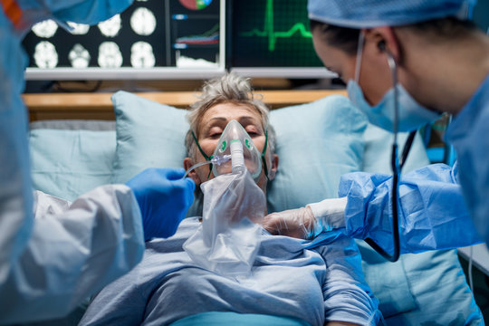 Doctors examining coronavirus infected patient lying on bed in hospital