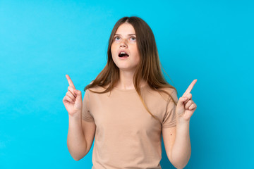 Ukrainian teenager girl over isolated blue background surprised and pointing up
