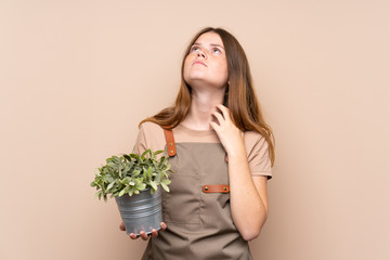 Ukrainian teenager gardener girl holding a plant thinking an idea