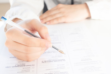 Signing documents for a pledge at home. Hands hold a pen over paper