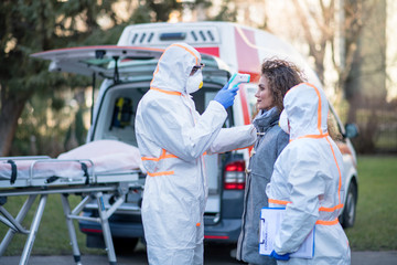 People with protective suits helping woman outdoors, coronavirus concept.