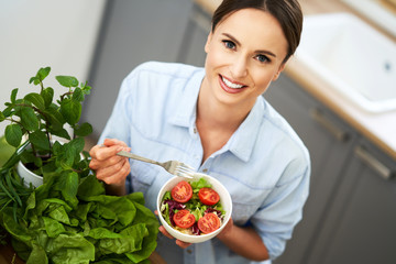 Healthy adult woman with green food in the kitchen