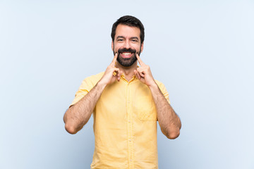 Fototapeta premium Young man with beard over isolated blue background smiling with a happy and pleasant expression
