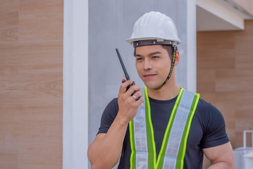Handsome and strong foreman.The foreman wearing a white helmet stood holding a radio communication...