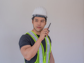 Handsome and strong foreman.The foreman wearing a white helmet stood holding a radio communication...