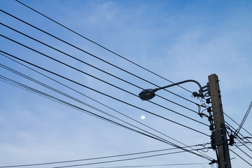 High voltage power electric wire pole with street light again moon on the sky background.