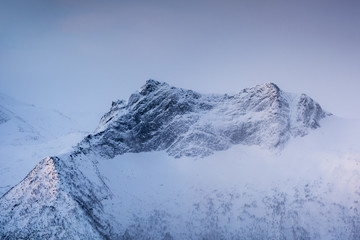 Fototapeta na wymiar Snowy mountain peak with light in foggy