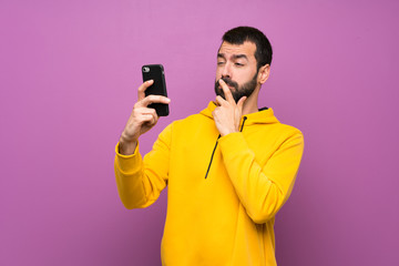 Handsome man with yellow sweatshirt thinking and sending a message