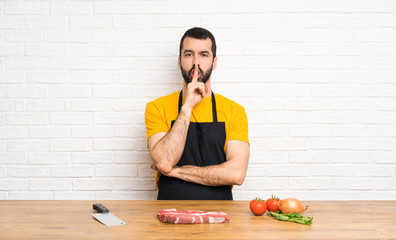 Chef holding in a cuisine showing a sign of silence gesture putting finger in mouth