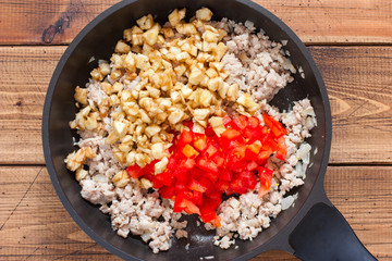 Step-by-step preparation of stuffed eggplants, step 2 - preparation of stuffing of minced meat, chopped eggplant, tomatoes, top view, horizontal
