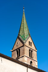 Fototapeta na wymiar Trento, closeup of the Bell tower of the Church of Santi Pietro e Paolo with green majolica roof tiles (XV century). Trentino-Alto Adige, Italy, Europe