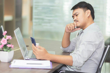 Asian business people are feeling stressed about the job with laptop and paper on the wooden table in the office. Asian men are worried when their work is unsuccessful.