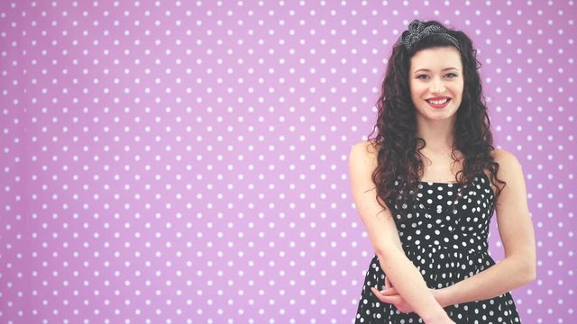 Beautiful young girl with kinky hair and black headband, wearing nice black polka-dots dress is looking at the camera, smiling.