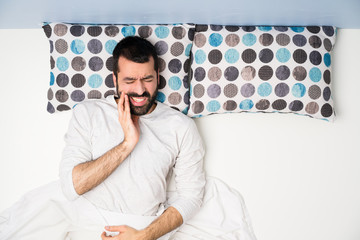 Man in bed in top view with toothache