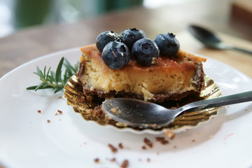 Tart blueberry on white dish and spoon on dish.