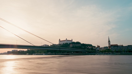 Landmark Capital of Slovakia - Bratislava Cityline with Castle, Church Tower, SNP Bridge over Danube River with Sailing Ships at Summer Sunset